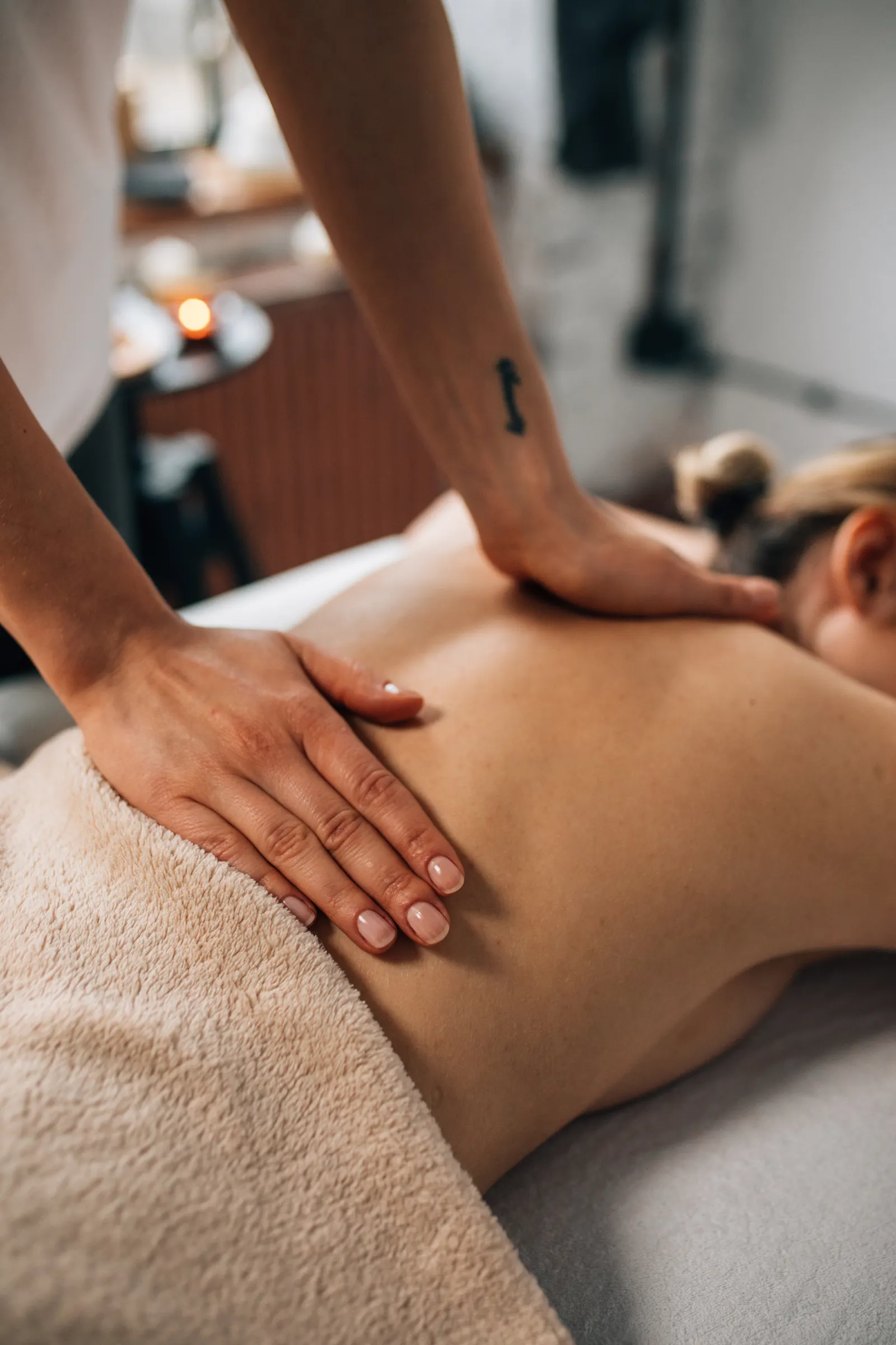 Close-up of hands massaging the back in a tranquil spa setting